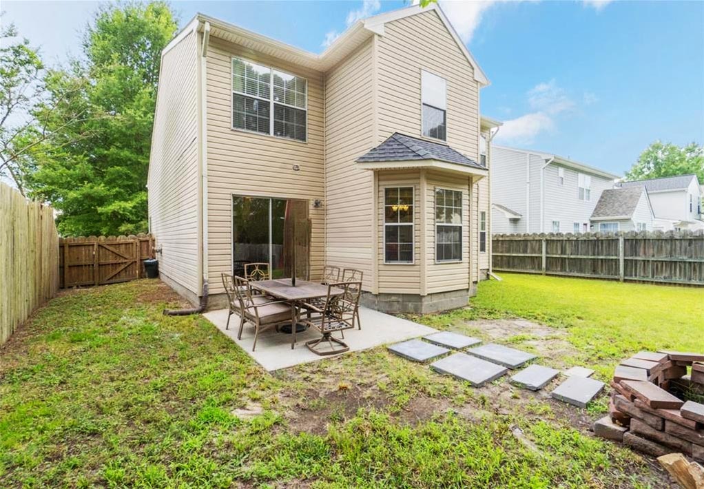 View from behind of the property located at 1428 Stalls Way, Virginia Beach, Virginia 23453, back yard, pavers, patio, outdoor furniture, fences, firepit, windows, sliding glass doors, bay window, grass, yard, neighbors
